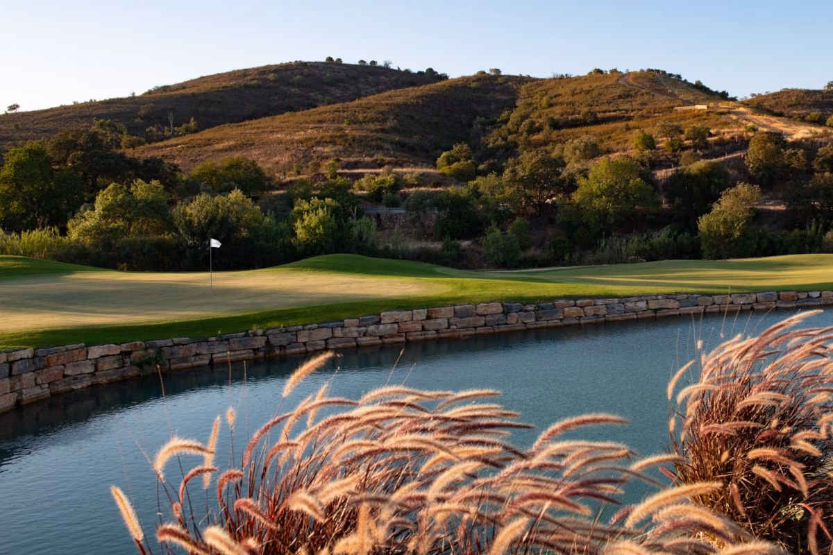 Lakeside green at Ombria Golf with stone wall and the Algarve hills beyond